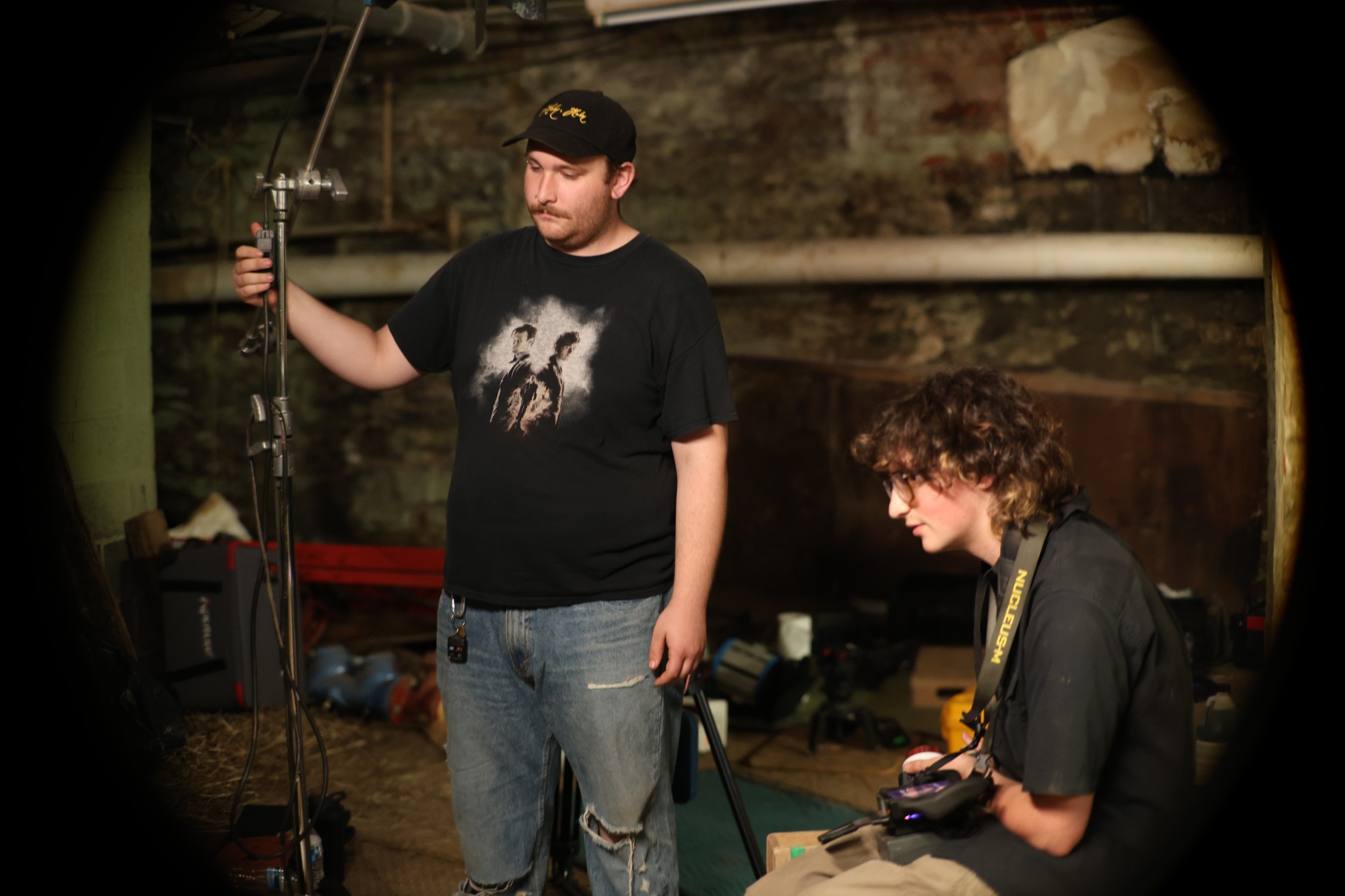 Behind the scenes: crew setting a light stand in a basement