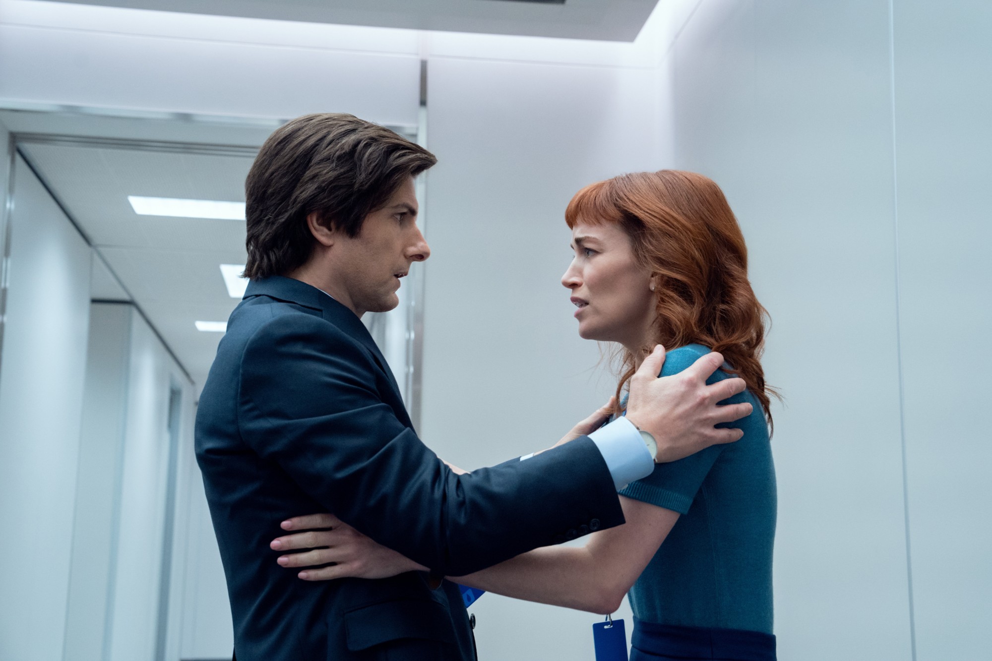 Severance: two coworkers face each other in a white corridor